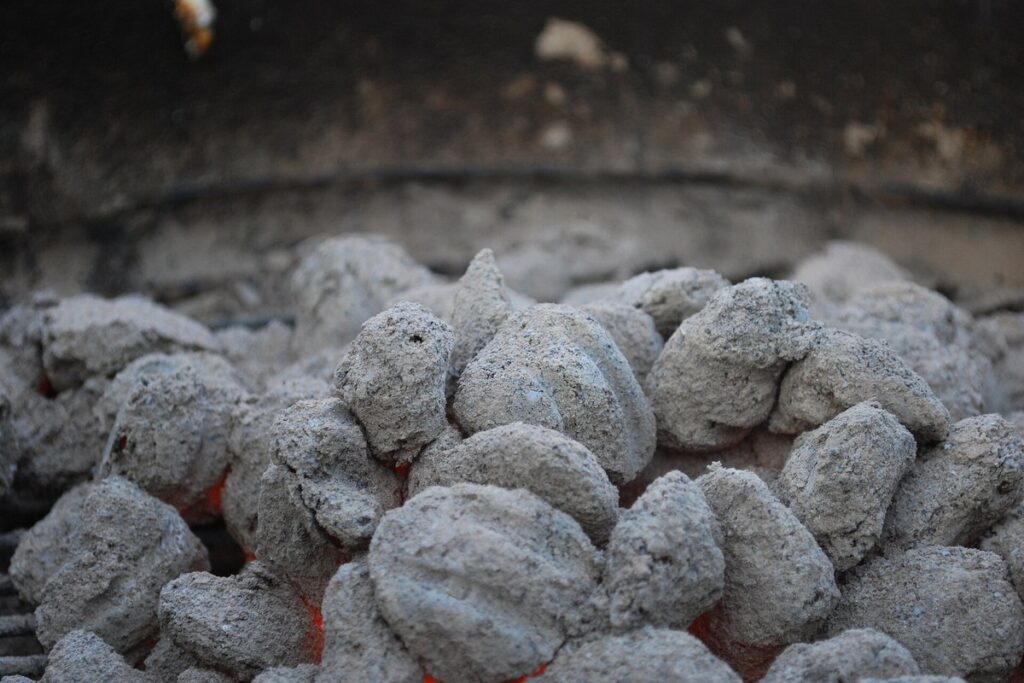Smoldering charcoal briquettes glowing with an ash layer