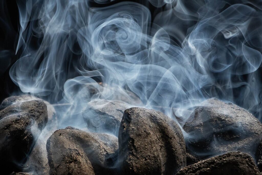 Coconut shell charcoal briquettes beginning to burn and emitting smoke