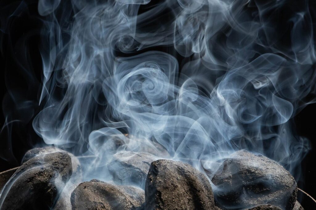 White smoke rising from charcoal as it starts to catch fire